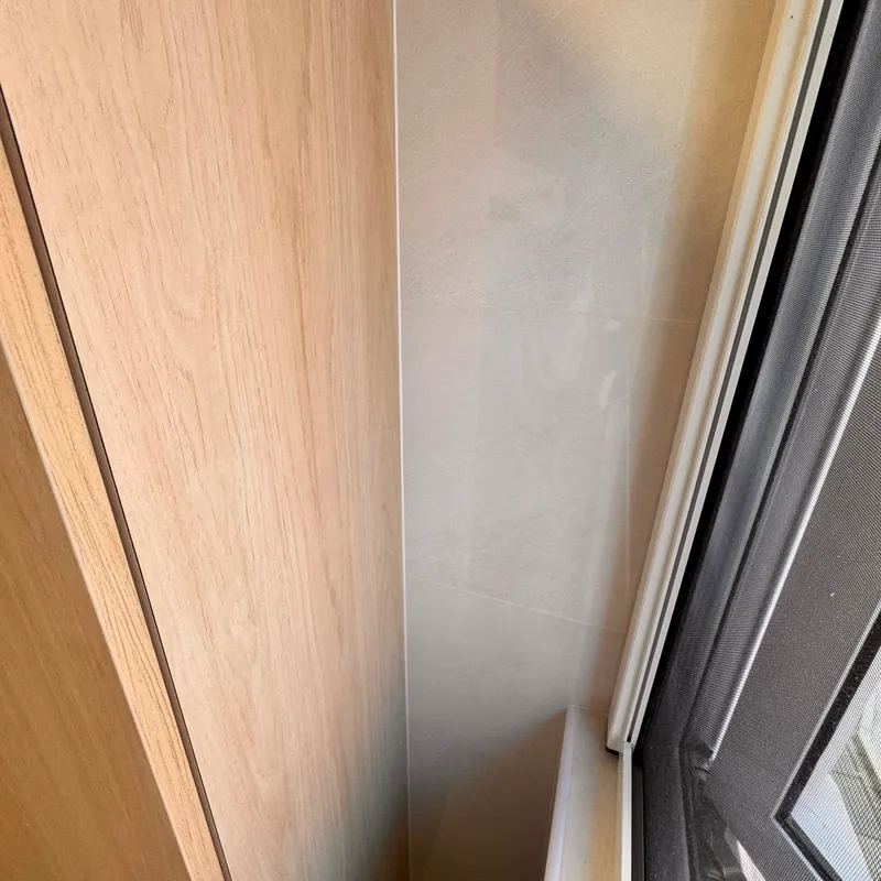 Close-up of the cabinet edge where it meets the tiled wall and window frame